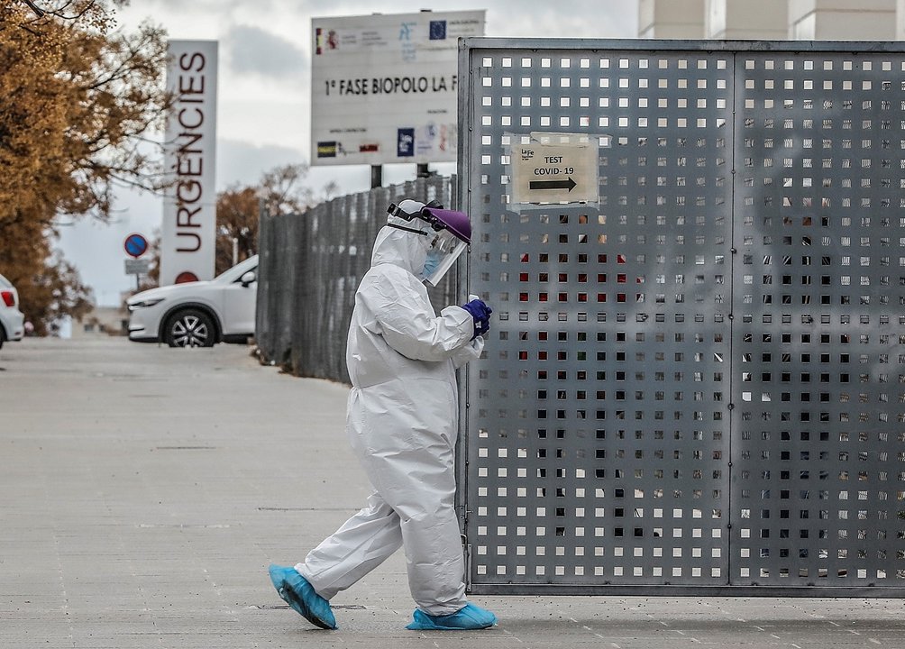 Un sanitario a los alrededores de la fila de vehículos para realizarse una prueba PCR de detección del coronavirus a las puertas del Hospital de Campaña próximo al de La Fe, en Valencia.