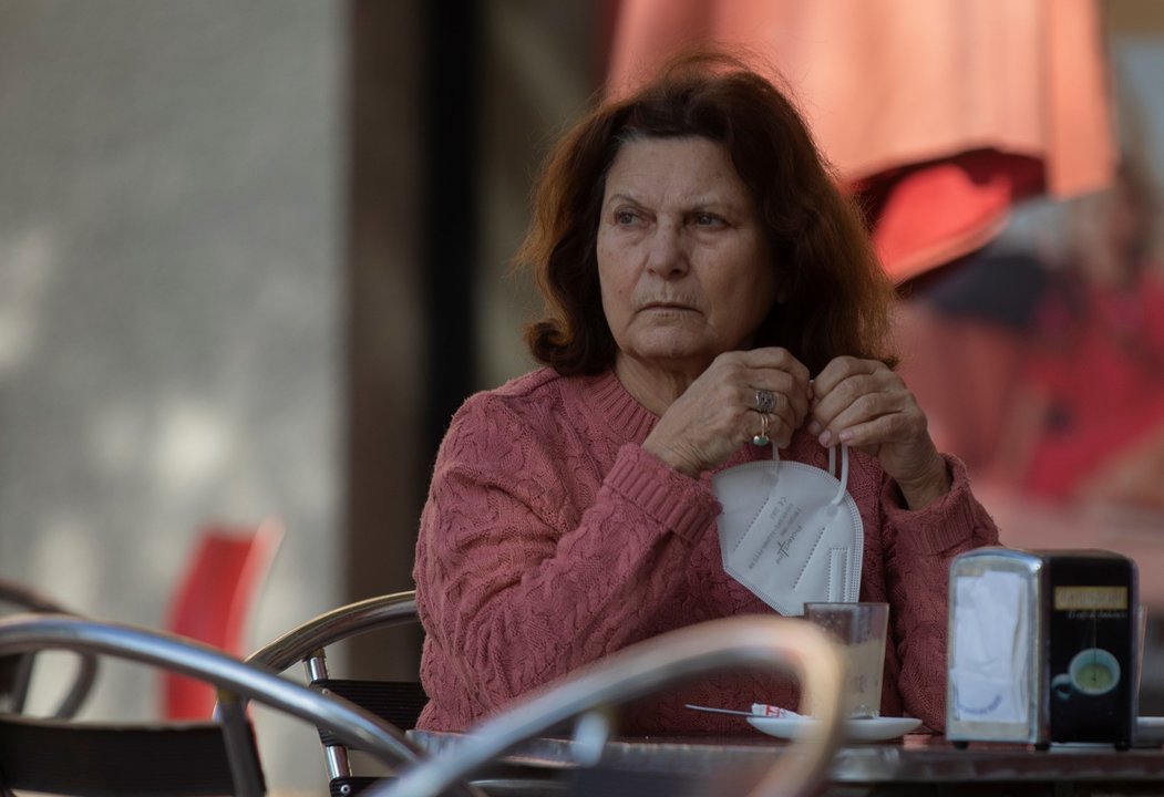Una mujer en la terraza de un bar con la mascarilla en la mano, mientras continúa el cierre perimetral en Montequinto, Dos Hermanas, (Sevilla, Andalucía, España), a 28 de enero de 2020.