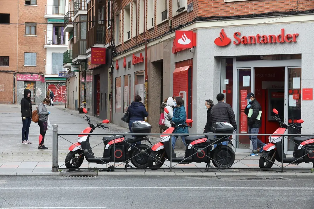 Varias personas esperan para entrar a una oficina del Banco Santander durante el inicio de la cuarta semana del estado de alarma decretado a consecuencia del coronavirus. En Madrid (Espa&ntilde;a), a 6 de abril de 2020.
