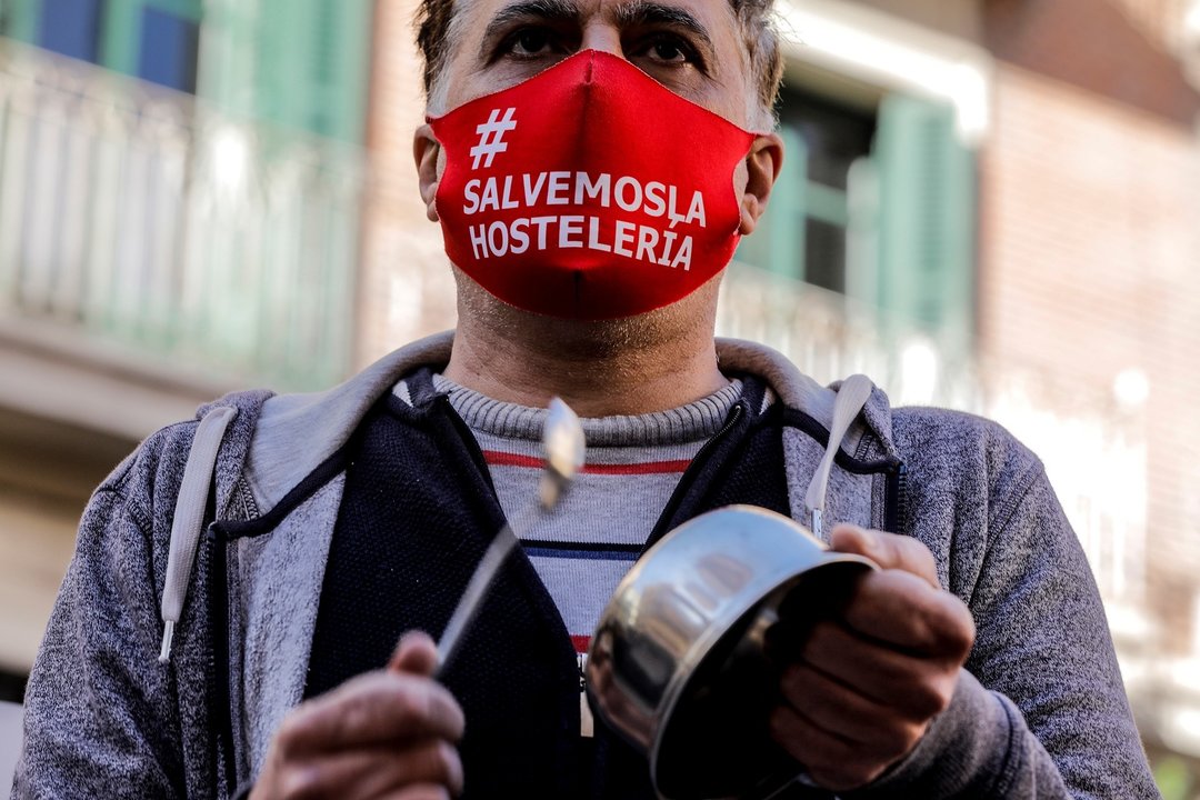 Un hombre con una mascarilla en la que se lee: `Salvemos la hostelería´ durante la cacerolada promovida por La Coordinadora Empresarial del Ocio y la Hostelería contra el cierre de la hostelería en la Comunidad Valenciana, en Valencia (España), a 21 de en