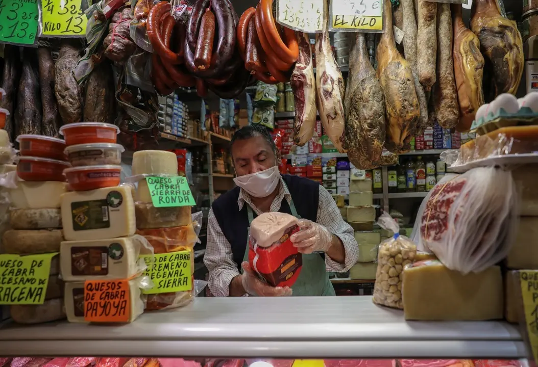Archivo - Un carnicero trabaja con mascarilla en un mercado.