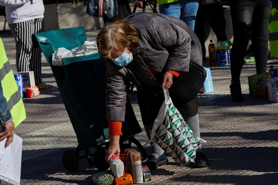 Una mujer recoge productos de alimentación donados por parte de la Despensa Solidaria de Chamberí (Madrid) durante la concentración y reparto de alimentos a familias vulnerables.