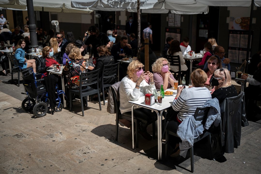 Varias personas en la terraza de un bar, el día en que se amplían a seis los comensales por mesa, a 12 de abril de 2021, en Valencia, Comunidad Valenciana (España).