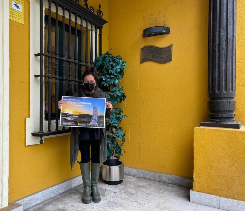 La concejala de Cultura de Torrelavega, Esther Velez, con el cartel de la exposici&oacute;n sobre las construcciones del hombre