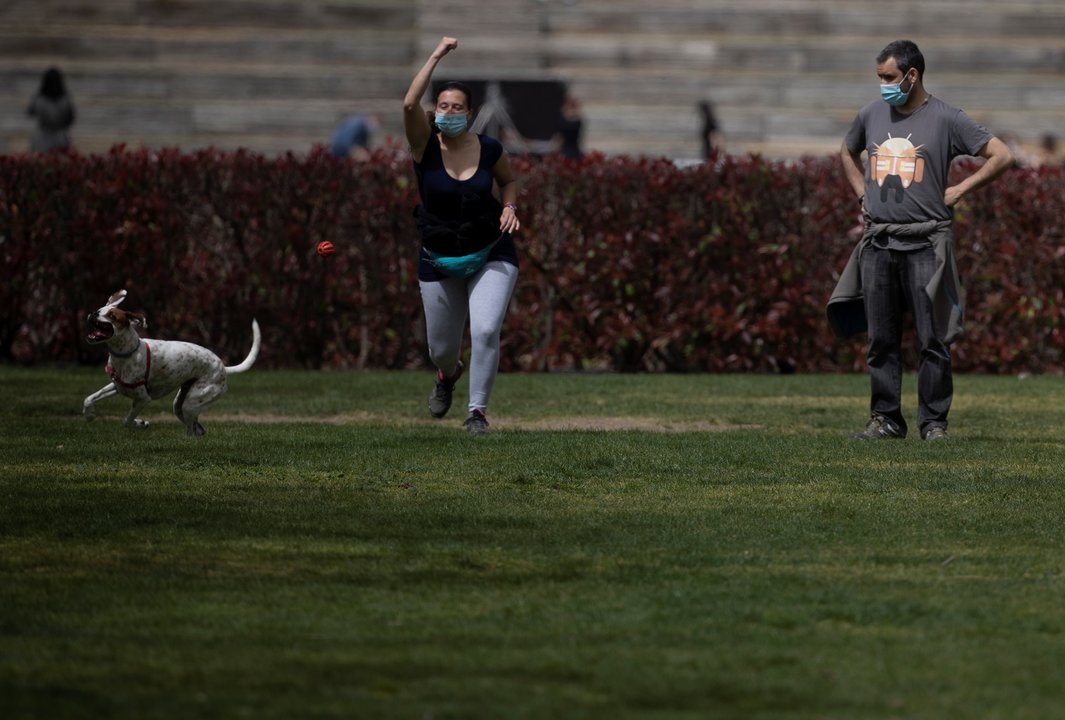 Archivo - Un hombre y una mujer, con mascarilla, juegan con un perro en el Parque del Manzanares, el día en que entra en vigor el uso obligatorio de mascarilla incluso con distancia de seguridad, en Madrid (España), a 31 de marzo de 2021. Hoy entra en vig