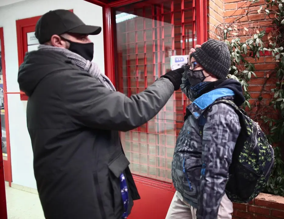 Archivo - Un trabajador toma la temperatura a un alumno antes de entrar a un colegio. 