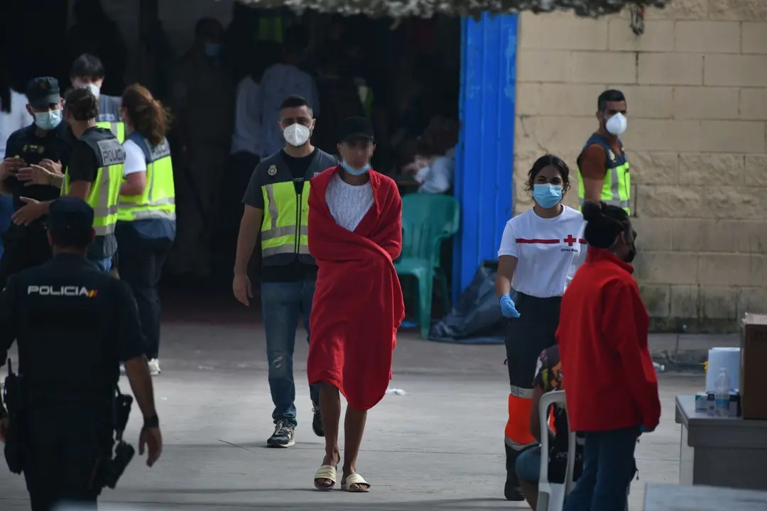 Agentes de la Polic&iacute;a Nacional acompa&ntilde;an a menores marroqu&iacute;es a las naves acondicionadas anexas a la frontera del Tarajal en Ceuta.