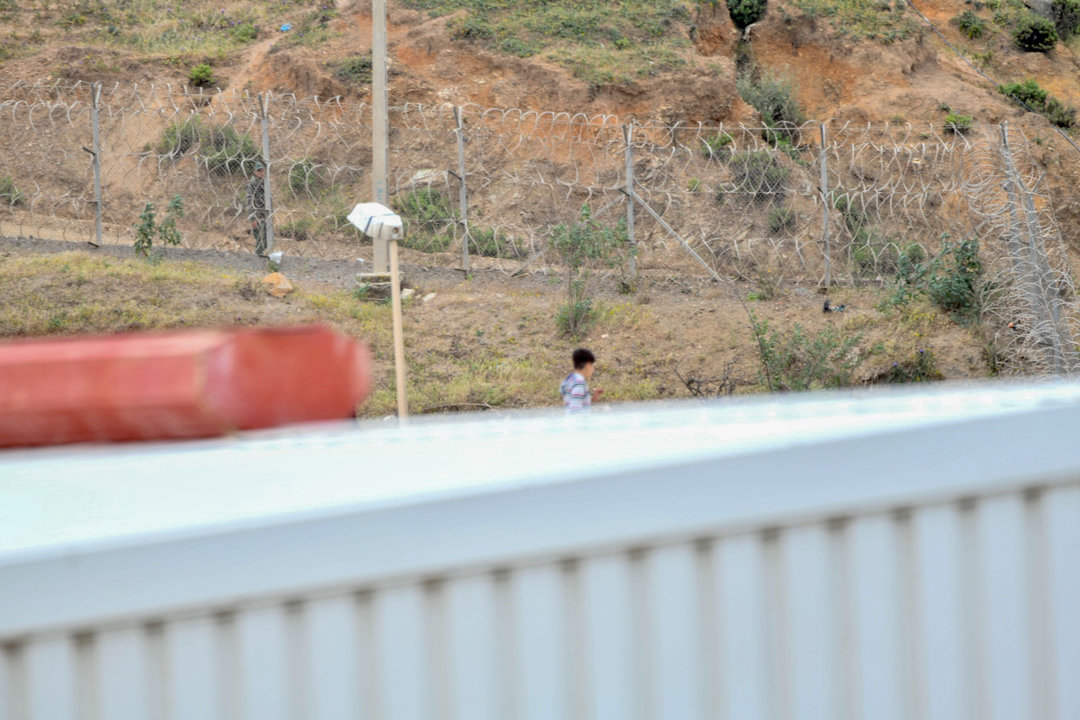 Un niño camina por un tejado al tratar de escapar de la nave de primera acogida del polígono del Tarajal, en Ceuta (España).