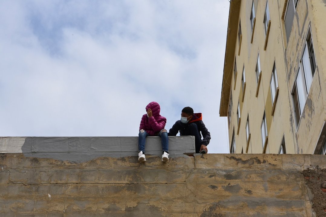 Dos niños sentados sobre un muro en la nave de primera acogida del polígono del Tarajal.