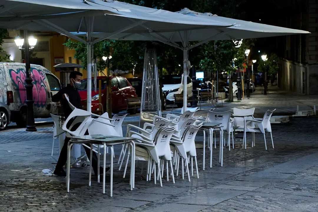 Una persona recoge la terraza de una cafeter&iacute;a 