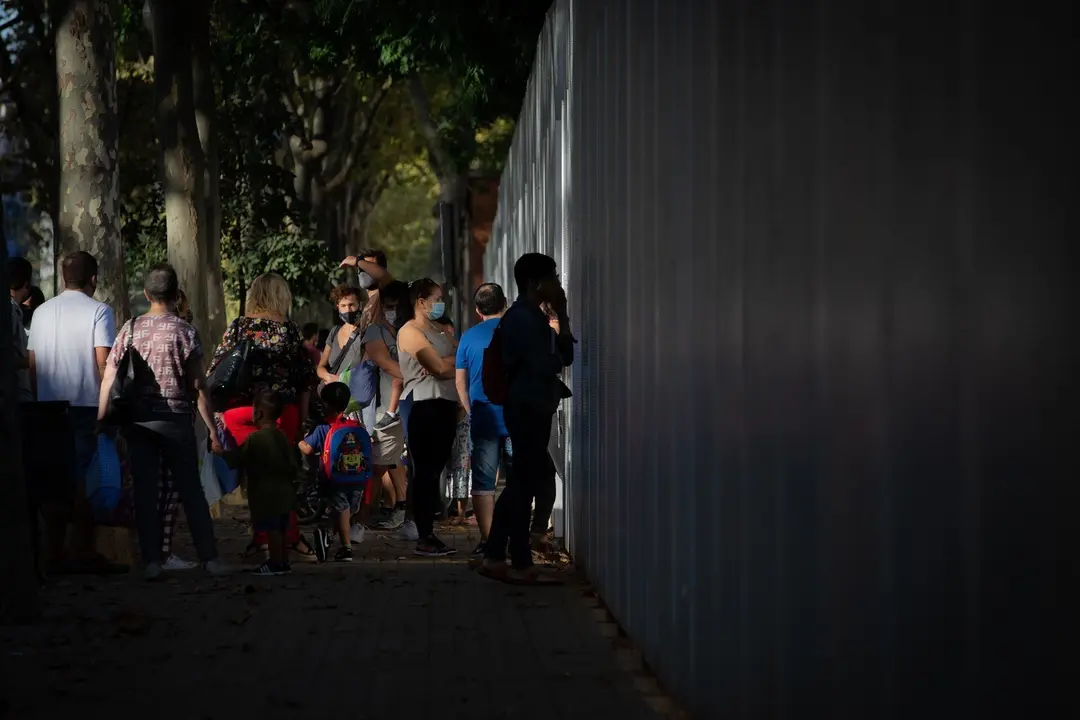 Archivo - Padres y alumnos esperan a las puertas de un colegio.