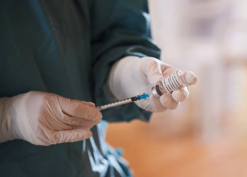 Archivo - Una profesional sanitaria sostiene un vial con la vacuna