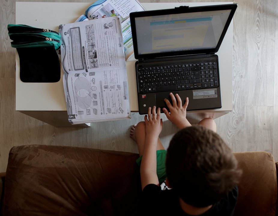 Archivo - Imagen de archivo de un alumno de Primaria haciendo los deberes con varios libros y un ordenador en su casa de Madrid