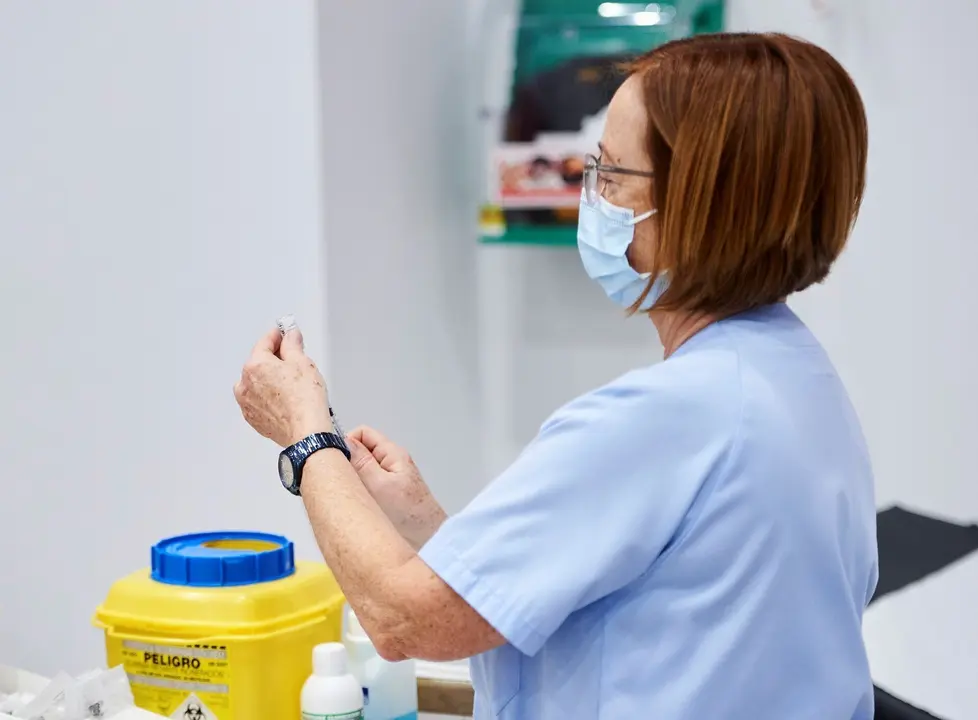 Archivo - Una trabajadora sanitaria sostiene una jeringuilla 