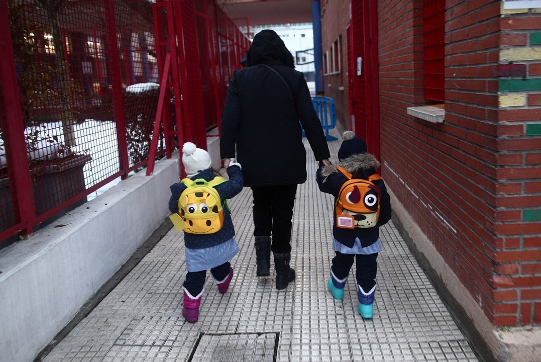 Archivo - Un adulto lleva de la mano a dos alumnos a un colegio de Madrid.