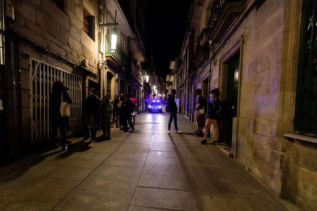 Un coche de polic&iacute;a pasa frente a varias personas en ambiente festivo, a 10 de julio de 2021, en Pontevedra, Galicia (Espa&ntilde;a).