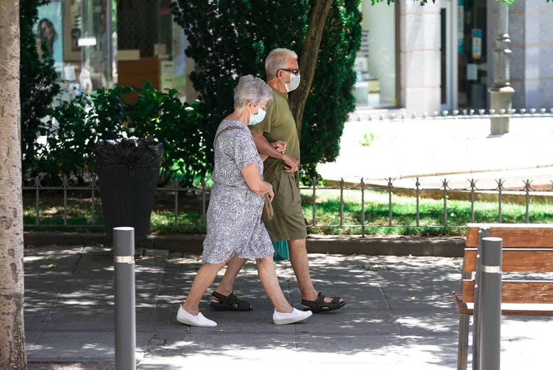 Una pareja de ancianos con mascarilla camina por la calle cogida del brazo, a 27 de julio de 2021, en Madrid, (España).