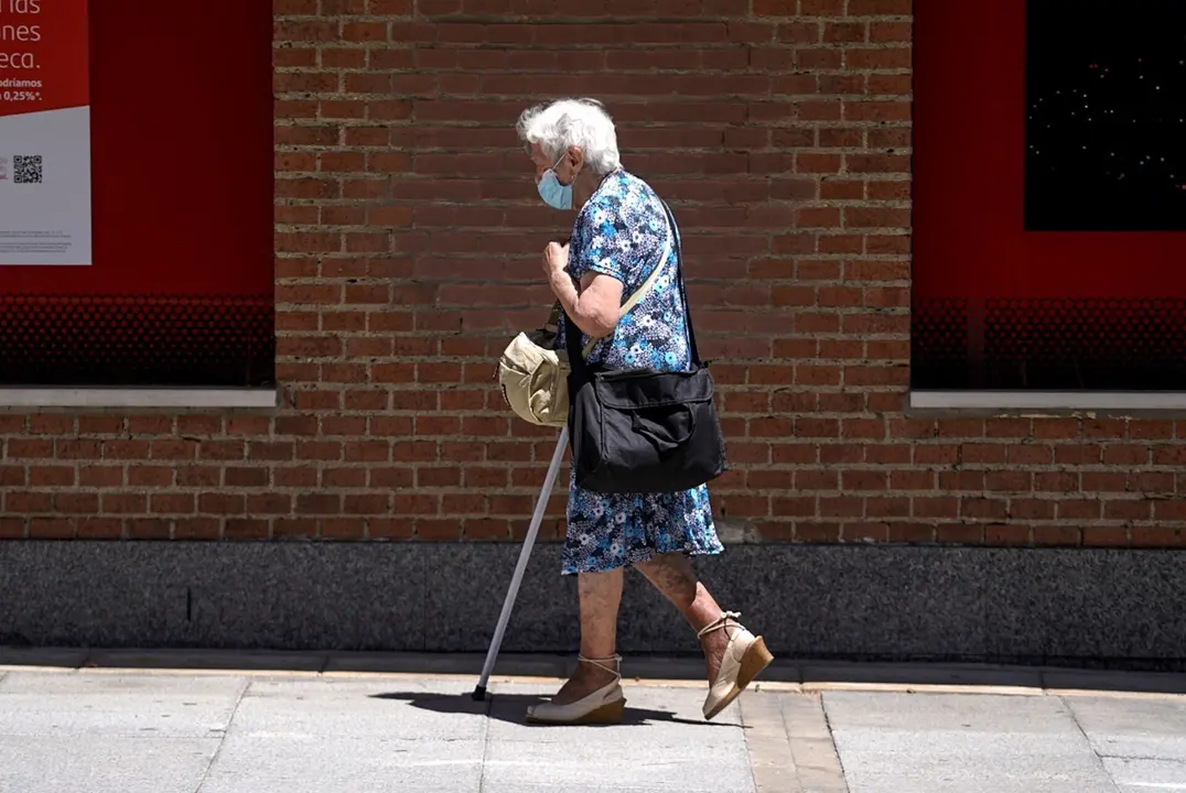 Una anciana con mascarilla camina por la calle ayudada de una muleta, a 27 de julio de 2021, en Madrid, (Espa&ntilde;a).