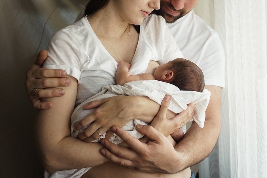  Father and mother with a newborn son. New young multi-generation family. Breast-feeding
