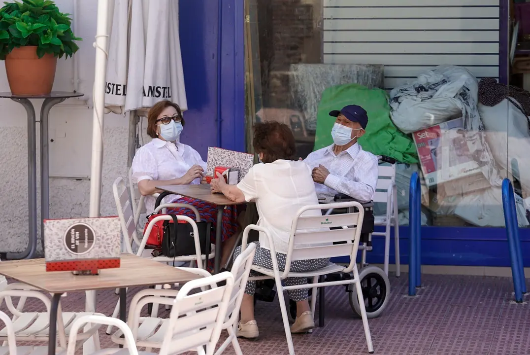 Ancianos con mascarilla conversan sentados en la terraza de un bar, a 27 de julio de 2021, en Madrid, (Espa&ntilde;a).