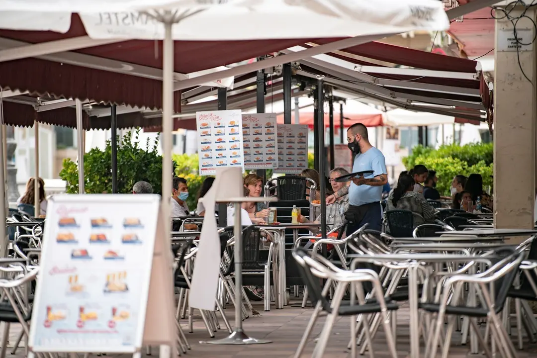 Archivo - Un camarero atiende una mesa en la terraza de una cafeter&iacute;a