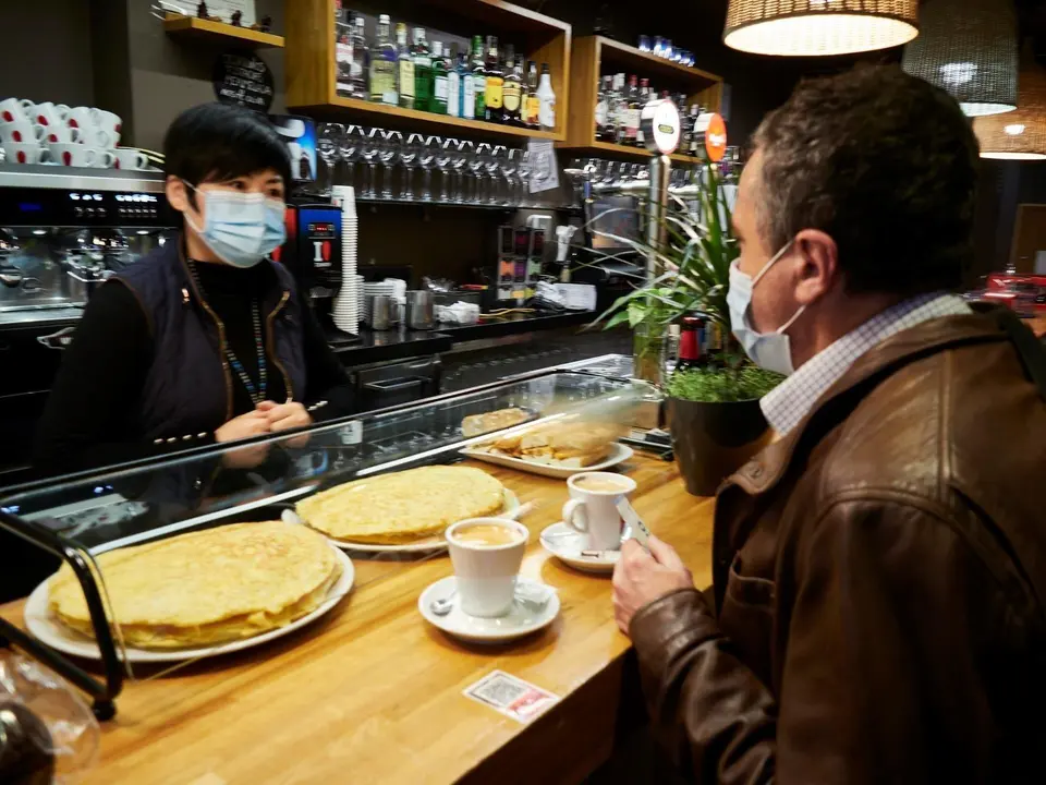 Archivo - Una camarera y un cliente en el interior de un bar