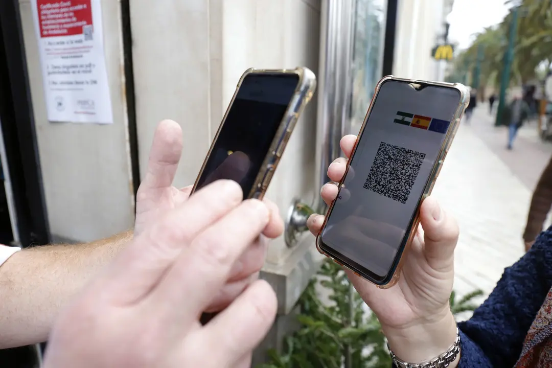 Un camarero pide certificado a los clientes en la puerta de un bar durante el primer d&iacute;a de petici&oacute;n de Certificados Covid-19 para la hosteler&iacute;a, a 20 de diciembre de 2021 en M&aacute;laga (Andaluc&iacute;a, Espa&ntilde;a)

