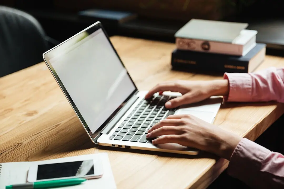 Close up portrait of male hands typing on laptop computer on a table indoors