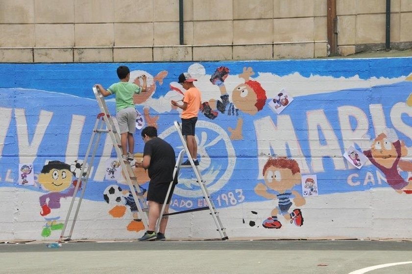 Niños realizando un mural en la pista deportiva de La Marisma en Astillero