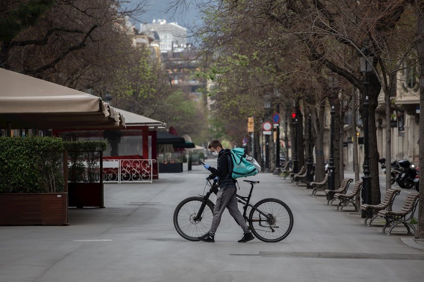 Un trabajador de Deliveroo en bicicleta por una calle de Barcelona, vacía durante el primer día laborable de la segunda semana desde que se decretó el estado de alarma en el país a consecuencia del coronavirus, en Barcelona.