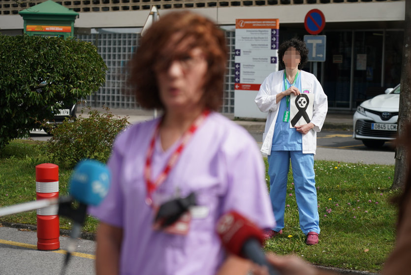Una sanitaria del Osakidetza (servicio vasco de salud)  del Hospital de Galdakao responde a los medios mientras otra profesional sostiene un lazo negro de luto en recuerdo a la enfermera de 52 años fallecida por Covid-19
