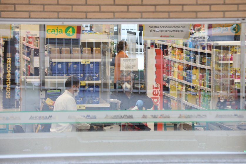 Un cajero de un supermercado AhorraMas trabaja protegido con mascarilla en plena crisis sanitaria por coronavirus donde los españoles llevan confinados en sus hogares más de una semana.