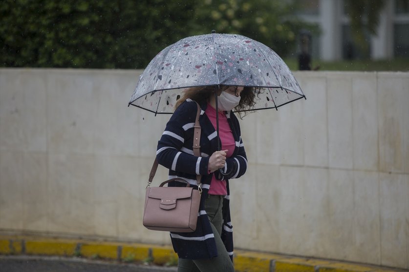 Una mujer con paraguas y mascarilla, durante la alerta amarilla por lluvia