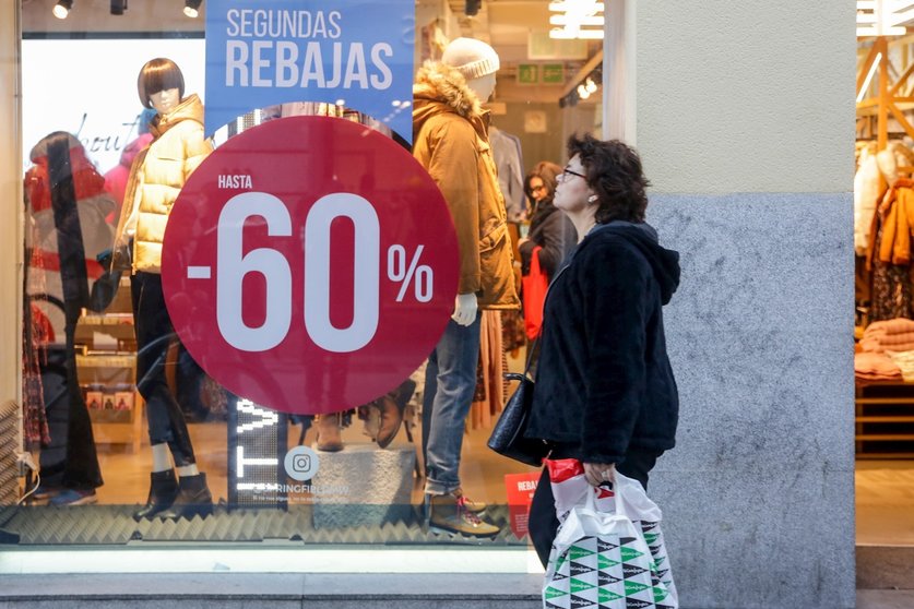 Una mujer pasea junto a una tienda de moda de Madrid, en la que se ofertan las segundas rebajas con ofertas de hasta el 60%.
