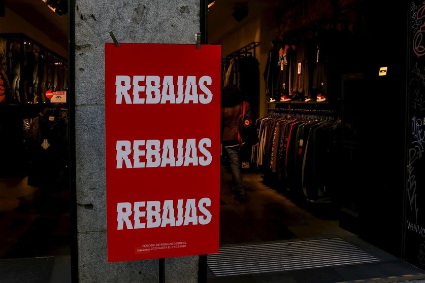 Un cartel en la entrada de una tienda de moda en el que se lee ' Rebajas'.