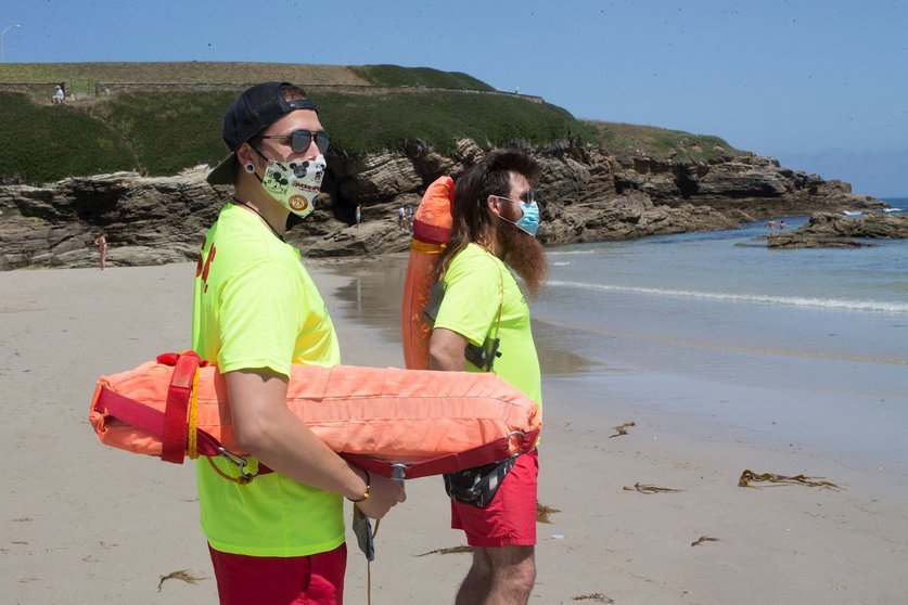 Dos socorristas protegidos con mascarilla vigilan la Playa de A Rapadoira en Foz, en la comarca de A Mariña, Lugo.