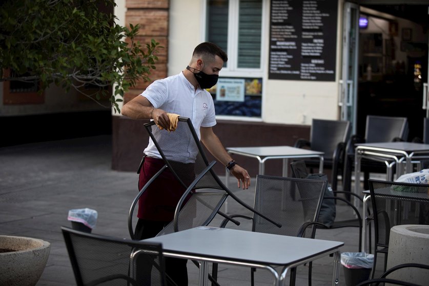 Un camarero recoge el mobiliario de la terraza de un bar
