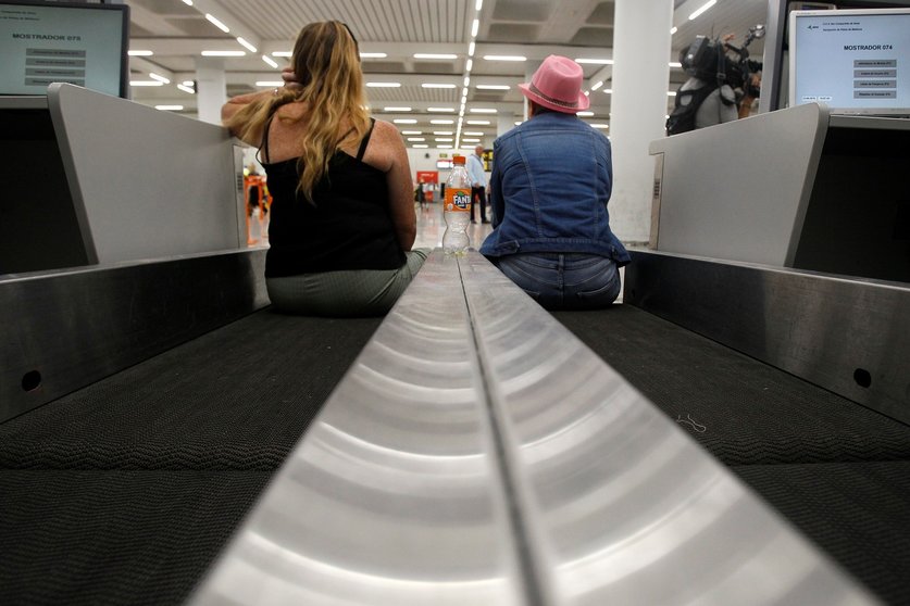 Dos turistas esperan sentadas en una cinta transportadora de maletas en el aeropuerto de Palma de Mallorca (Baleares), horas después de que la compañía británica Thomas Cook anunciase su quiebra y de que varios de sus vuelos fuesen cancelados, a 23 de sep
