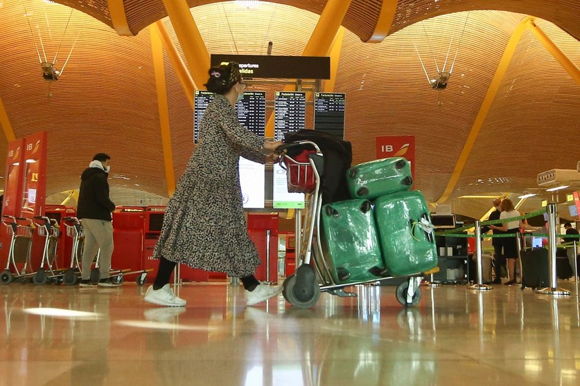 Una mujer camina con varias maletas en un carro en la terminal T4 del Aeropuerto Adolfo Suárez Madrid-Barajas