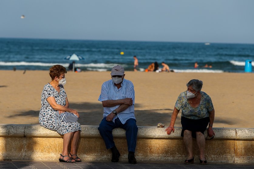 Archivo - Tres personas mayores descansan en el paseo marítimo de la playa de la Malvarrosa.