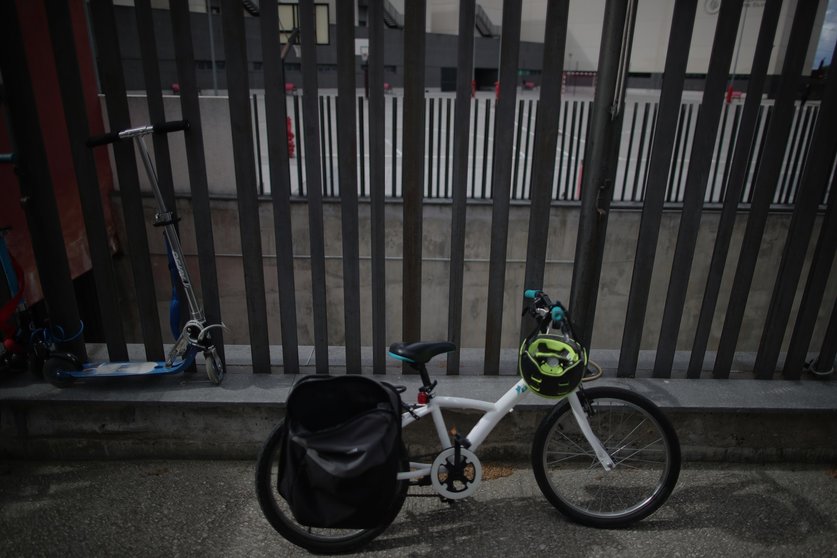 Archivo - Una bicicleta y un monopatín se encuentran apoyados en una de las verjas de un colegio
