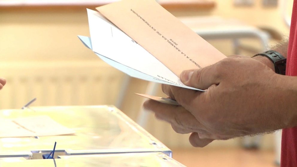 Un elector con las papeletas junto a la urna