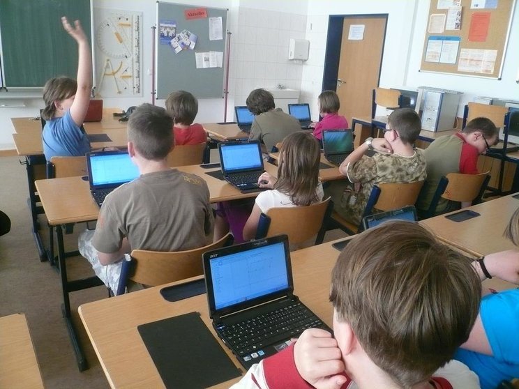 Estudiantes con ordenadores en un aula.