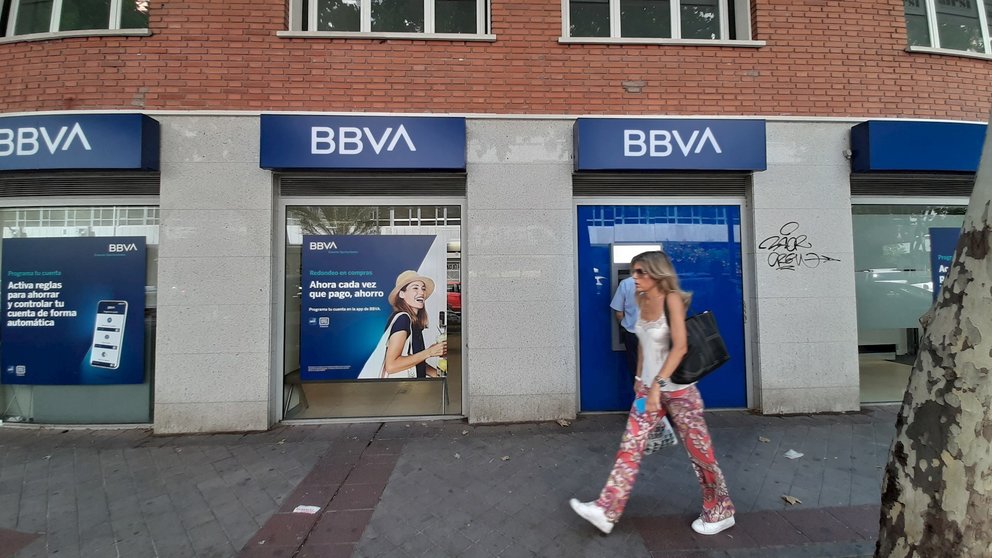 Una mujer pasa una oficina bancaria con el nuevo logo del BBVA en Madrid.