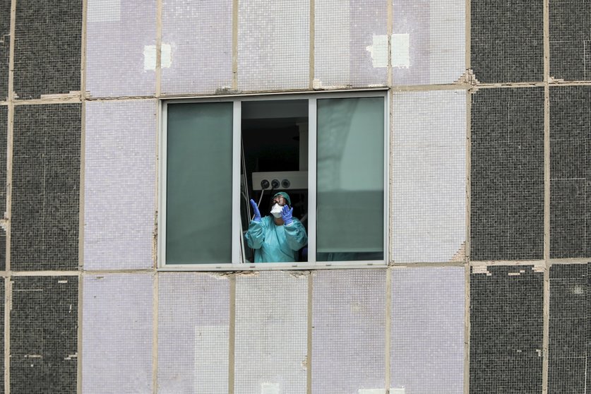 Una sanitaria del Hospital de La Paz totalmente protegida saluda y agradece el apoyo desde una de las ventanas del centro donde se lucha contra el coronavirus, en Madrid (España), a 18 de marzo de 2020.