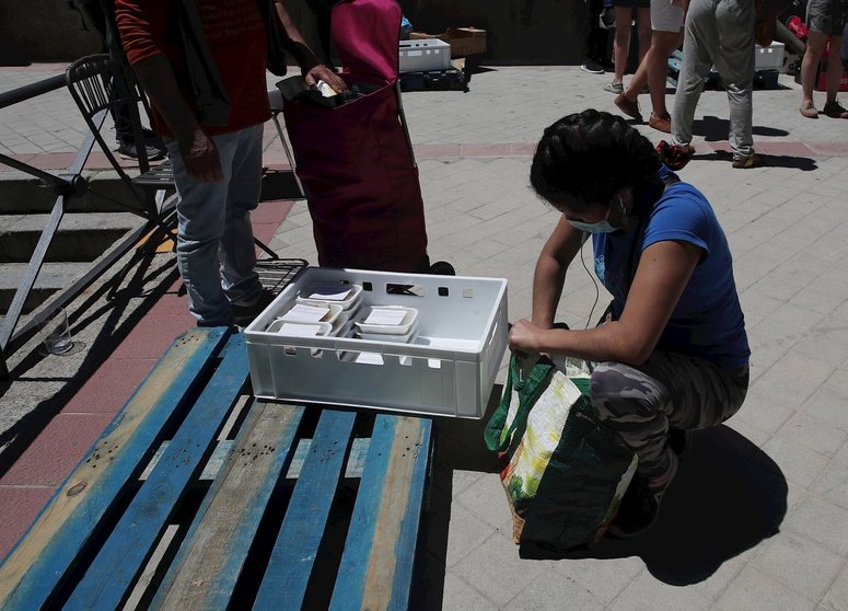Una mujer recoge productos a las puertas de la Parroquia Santa María Micaela donde han acudido para recibir una ayuda alimentaria d