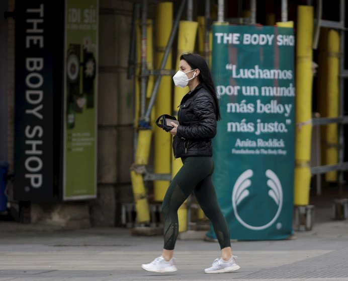 Una mujer camina con una mascarilla por la capital donde desde este pasado lunes las 2.882 farmacias madrileñas han entregado de forma gratuita siete millones de mascarillas FFP2 modelo KN95 entre la población de la Comunidad de Madrid  