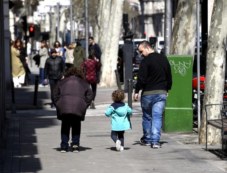 Unos padres pasean junto a su hija por la calle