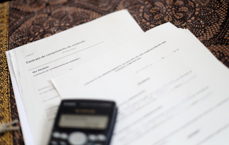 Una calculadora sobre un contrato de compraventa de vivienda y un contrato de arrendamiento.