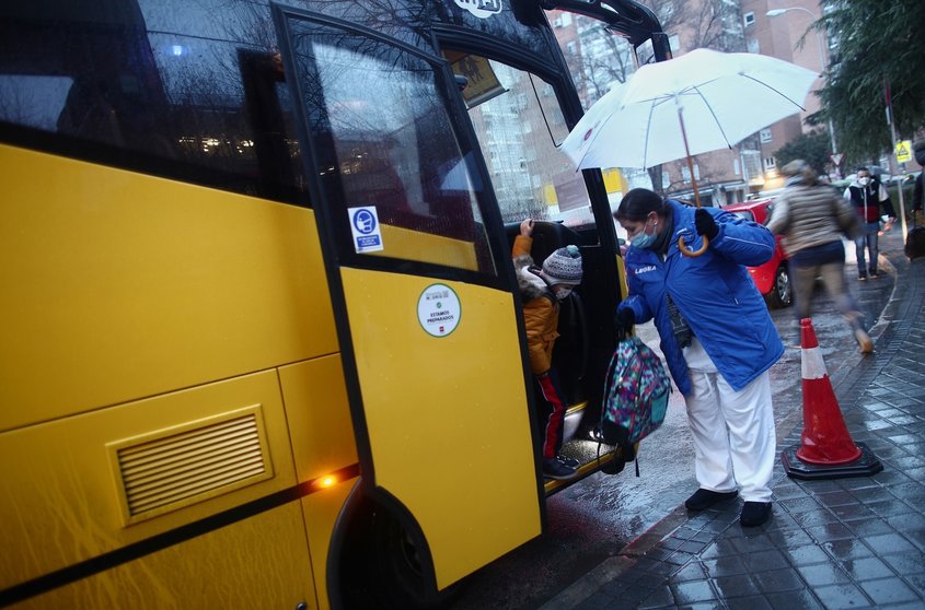 Una trabajadora ayuda a bajar a un alumno de un autobús escolar del colegio Arcangel Rafael el día de la reapertura de los centros educativos tras la gran nevada registrada por el paso de ‘Filomena’, en Aluche, Madrid, (España), a 20 de enero de 2021. El 